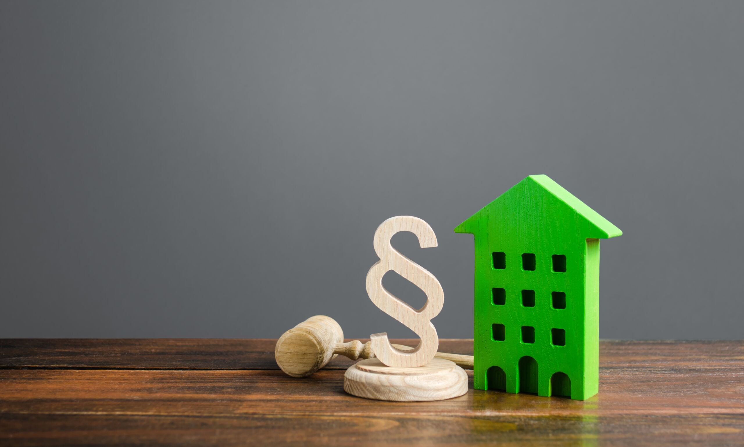Green house and paragraph figurine with a judge hammer. Litigation in housing and real estate disputes. Norms and rules for construction, maintenance. Encouraging green and energy-saving technologies.